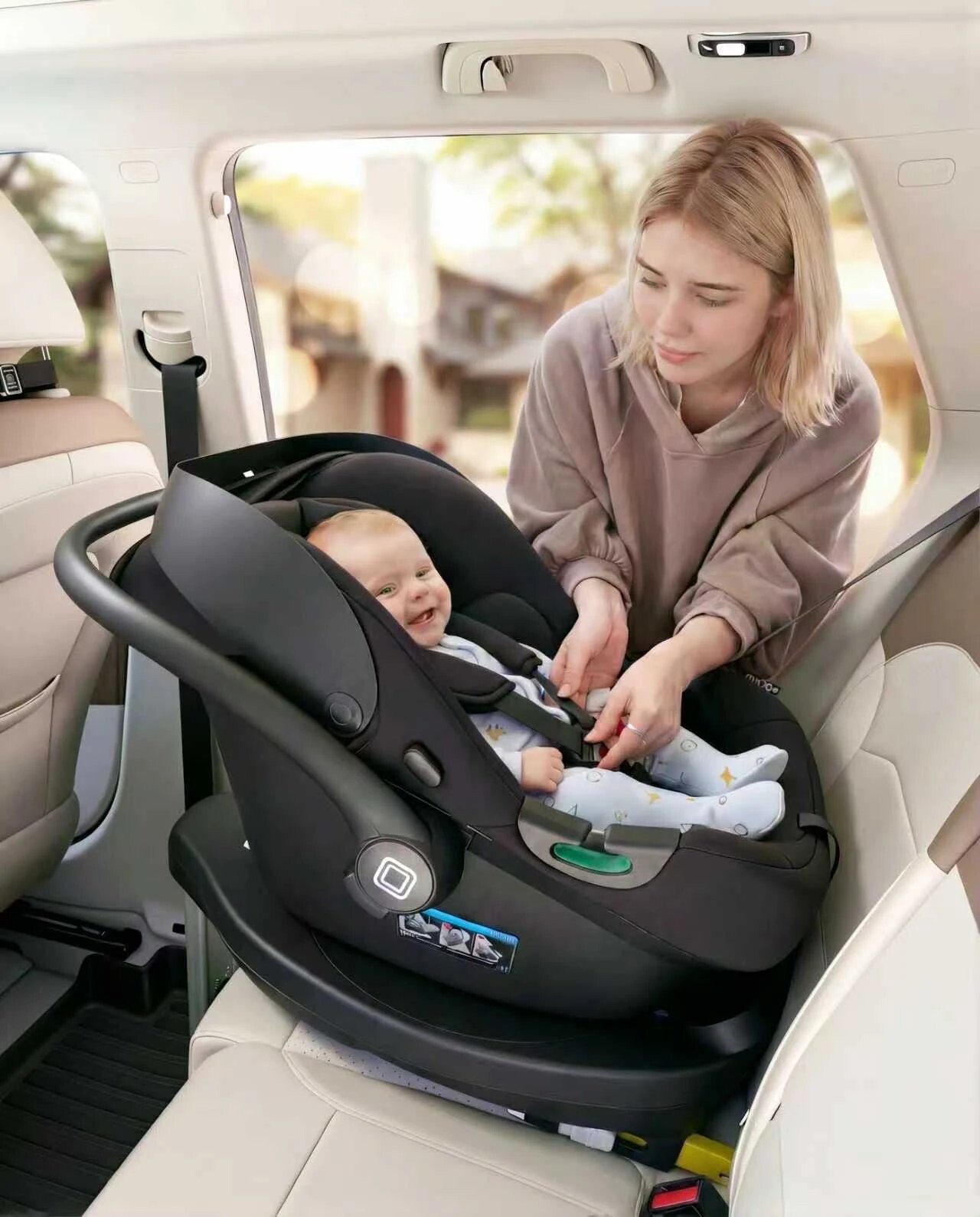 Mutter schnallt ihr Baby in der MOON Babyschale LOLA auf der 360° IQ-Isofix Base im Auto an